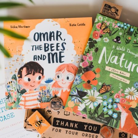 The image shows the contents of the book box. There are two books, one has an orange cover and illustrations of a boy and a girl. The other book has a green cover and shows animals and flowers.