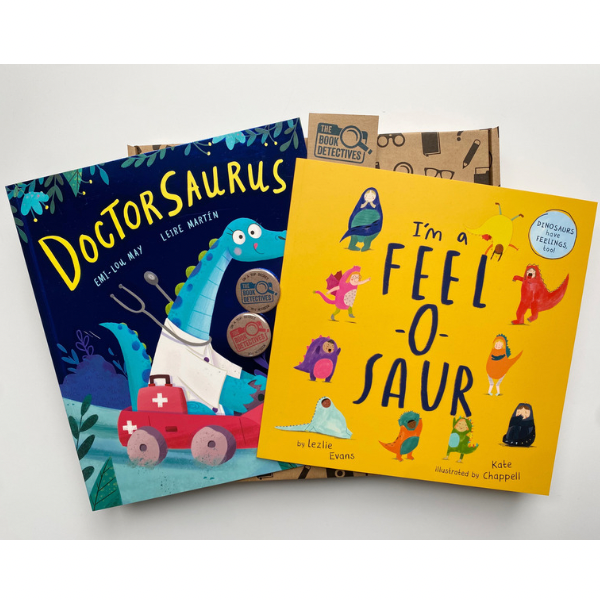 The image shows the contents of the book box. There are two books photographed on top of one of The Book Detectives’ postal boxes. Doctorsaurus has a blue cover and there is an illustration of a blue dinosaur wearing a doctor’s coat and driving a red car. I’m A Feel-O-Saur has a yellow cover and there are illustrations of dinosaurs around the outside. Each dinosaur represents a different emotion.